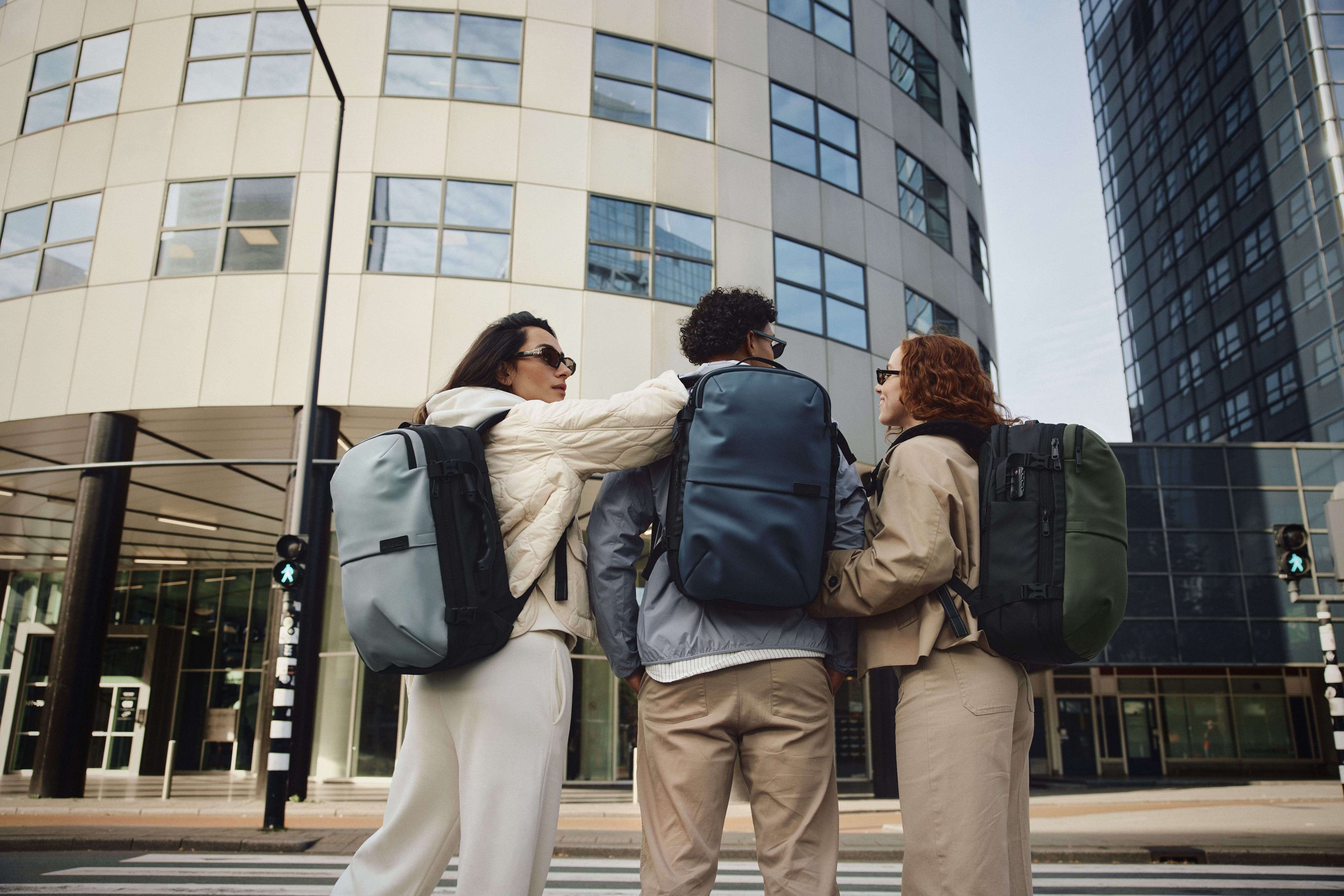 Three people with backpacks standing in front of a modern building